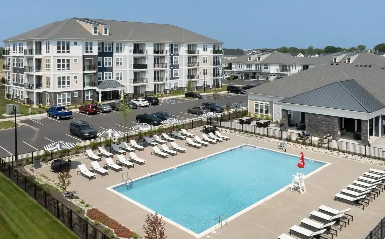 Aerial view of the sparkling pool, lounge area, parking lot and the apartment complex of The Wexford